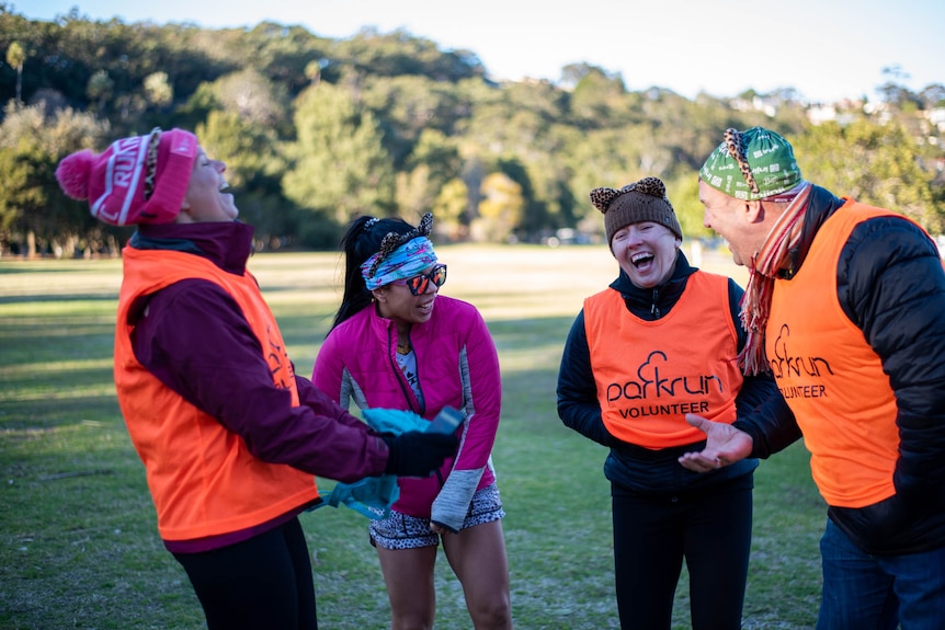 parkrun volunteers stand in a circle and laugh.