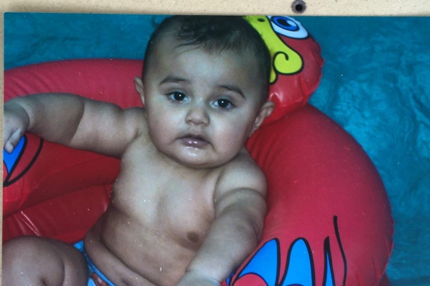 Baby Baden Bond sits in a inflatable toy chair, date and location unknown.