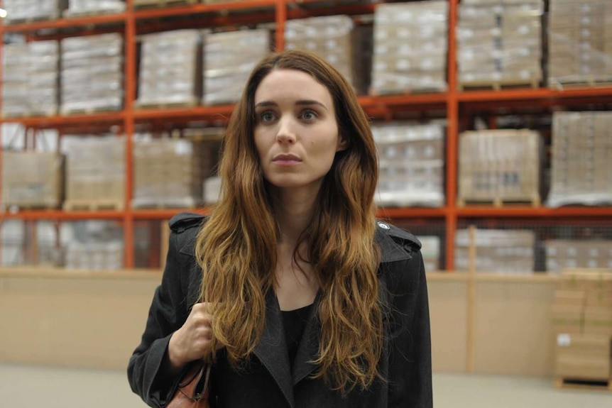 In a packing warehouse, Mara's character stares off camera.