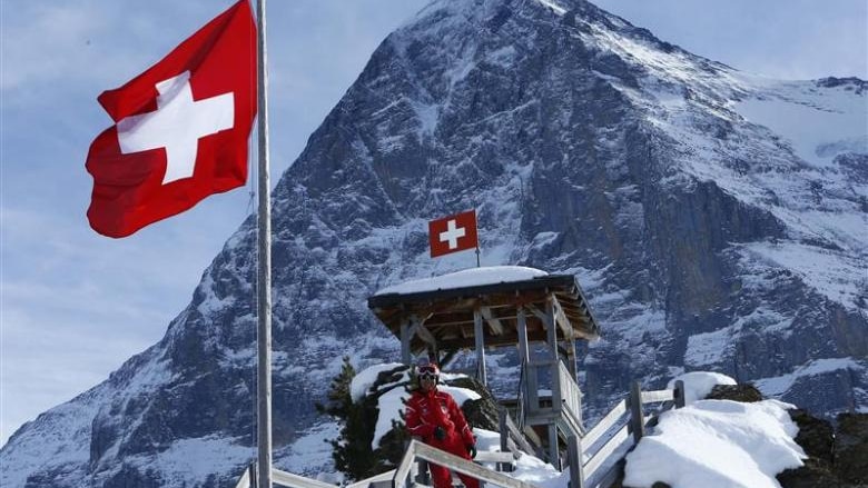 Swiss flag flying in mountains at a ski resort.