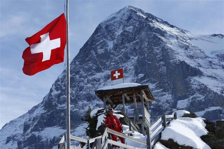 Swiss flag flying in mountains at a ski resort.