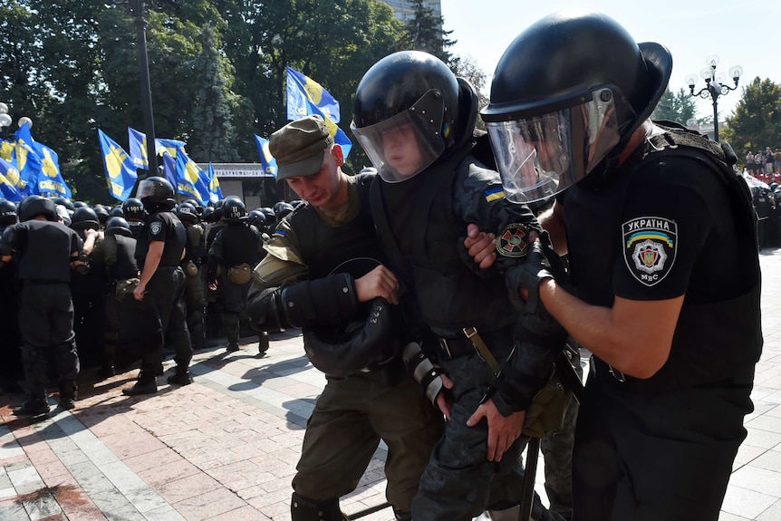 Ukraine policemen help a wounded colleague during clashes