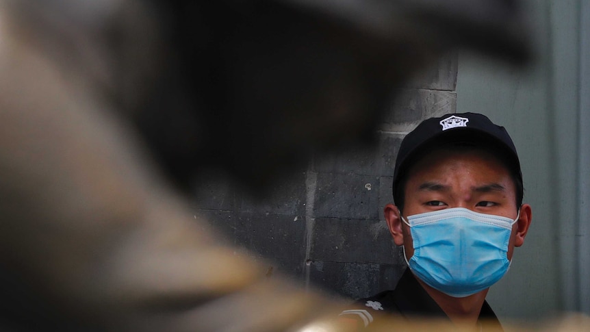 A security guard wearing a face mask to protect against the new coronavirus stands on duty near a statue in China.