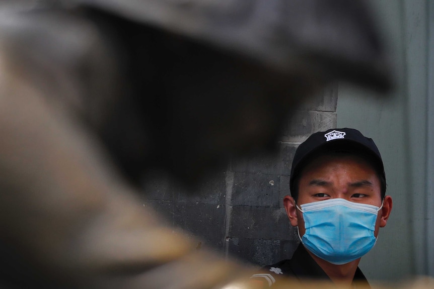 A security guard wearing a face mask to protect against the new coronavirus stands on duty near a statue in China.