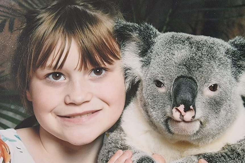 A girl with a beautiful smile holds a koala