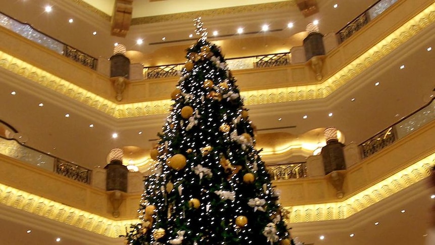 An Emirati man walks past an 11-million-dollar Christmas tree