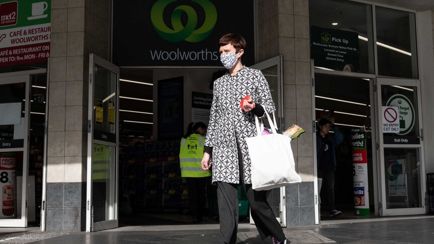 a shopper wearing a face mask leaving a woolworths shop