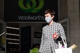 a shopper wearing a face mask leaving a woolworths shop