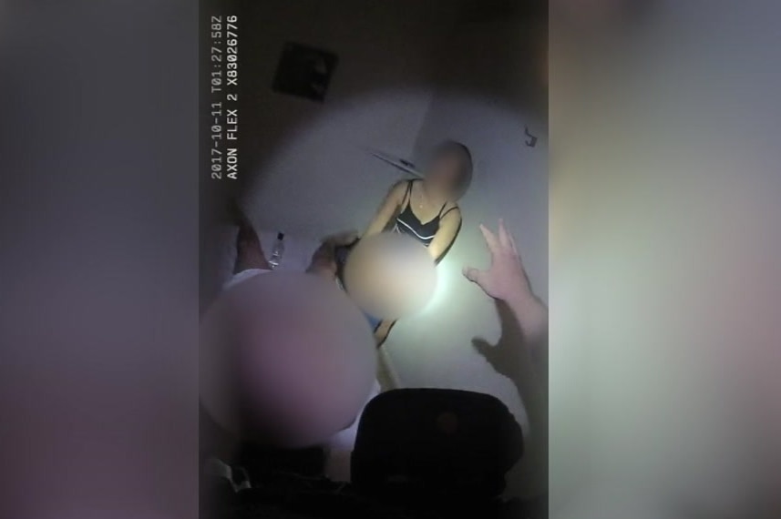 Police bodycam with blurred woman and man on bed.