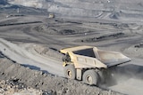 A large dump truck drives through an open-cut coal mine.