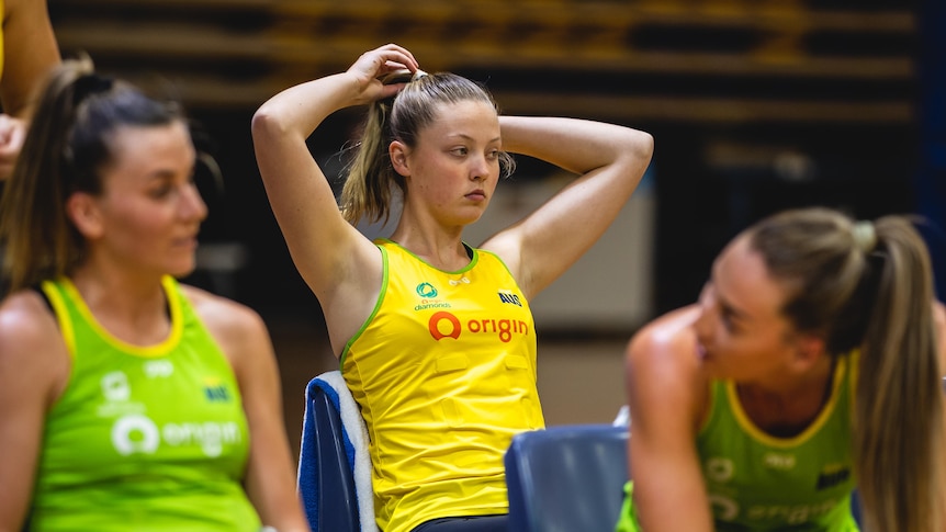 Sophie Dwyer rests her hands on her head and fiddles with her hair as she watches her team mates play a practice match