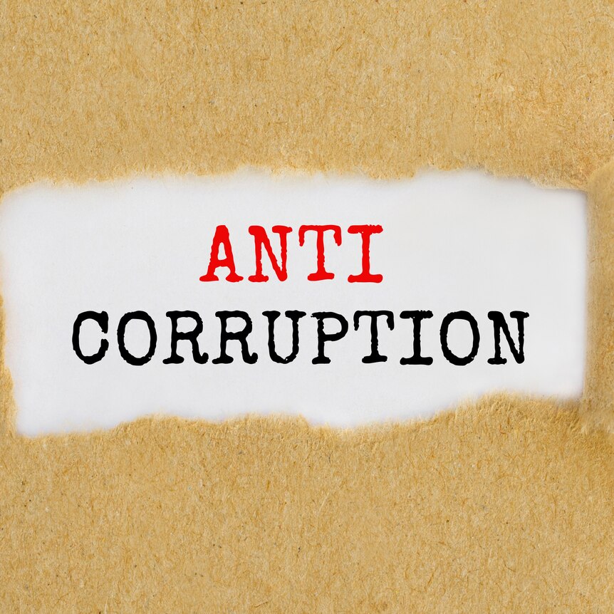 Anti-Corruption behind torn piece of brown paper