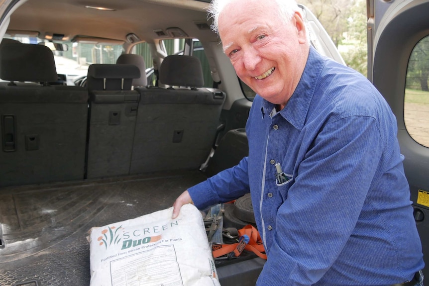 A smiling older man shows off a sack in his boot