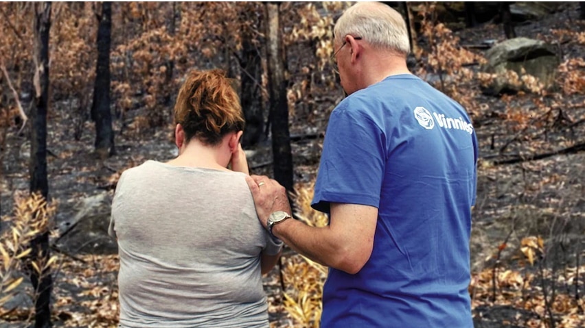 A volunteer for charity Vinnies comforts a woman as she looks at her burnt property