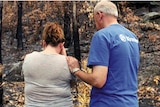A volunteer for charity Vinnies comforts a woman as she looks at her burnt property