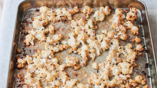 Baking tray of crumbled cauliflower, freshly roasted with Parmesan cheese and garlic. A snack or side.