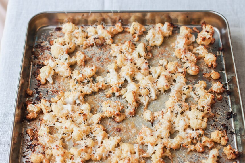 Baking tray of crumbled cauliflower, freshly roasted with Parmesan cheese and garlic. A snack or side.
