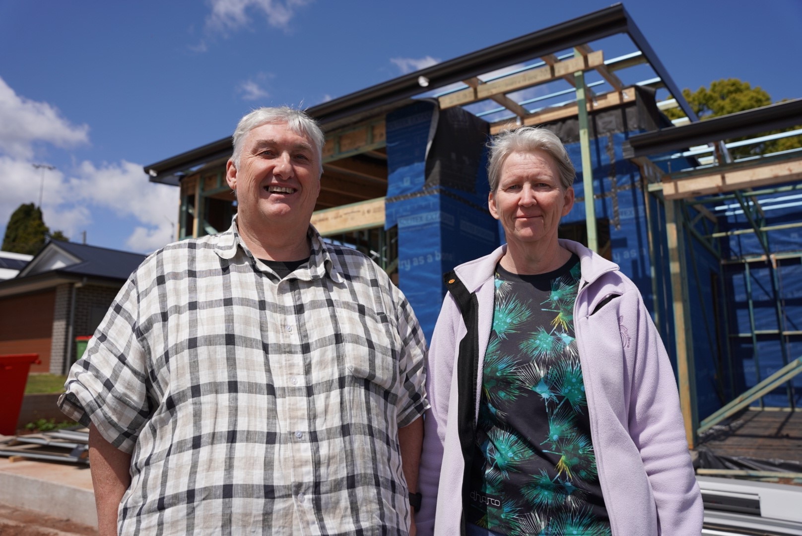A man with a chequered shirt standing next to a woman with a pink jumper
