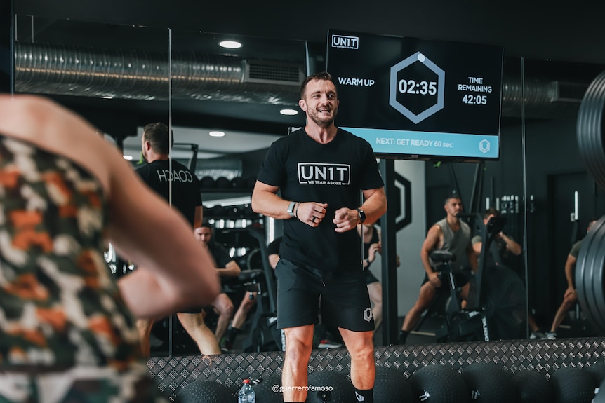 A man in gym gear seated on the ground ready to exercise