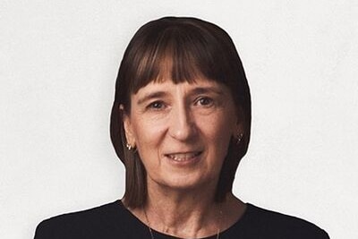 A close up of a woman looking directly in the camera and smiling, with a white background