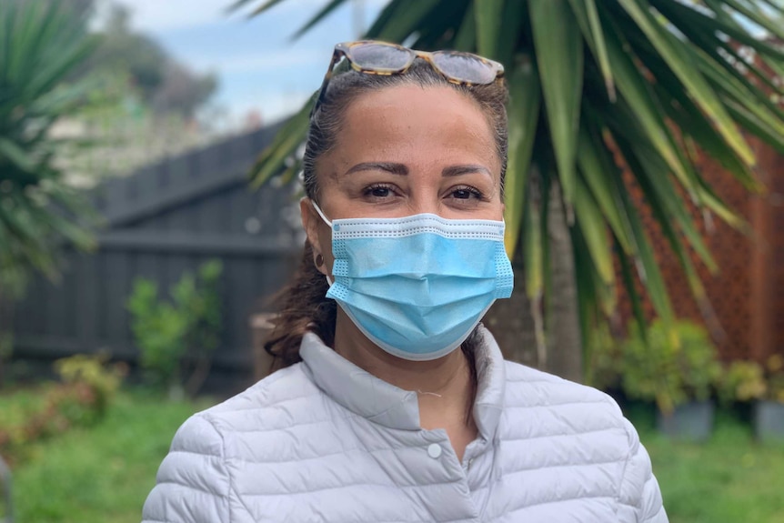 A woman in a face mask standing in a garden.