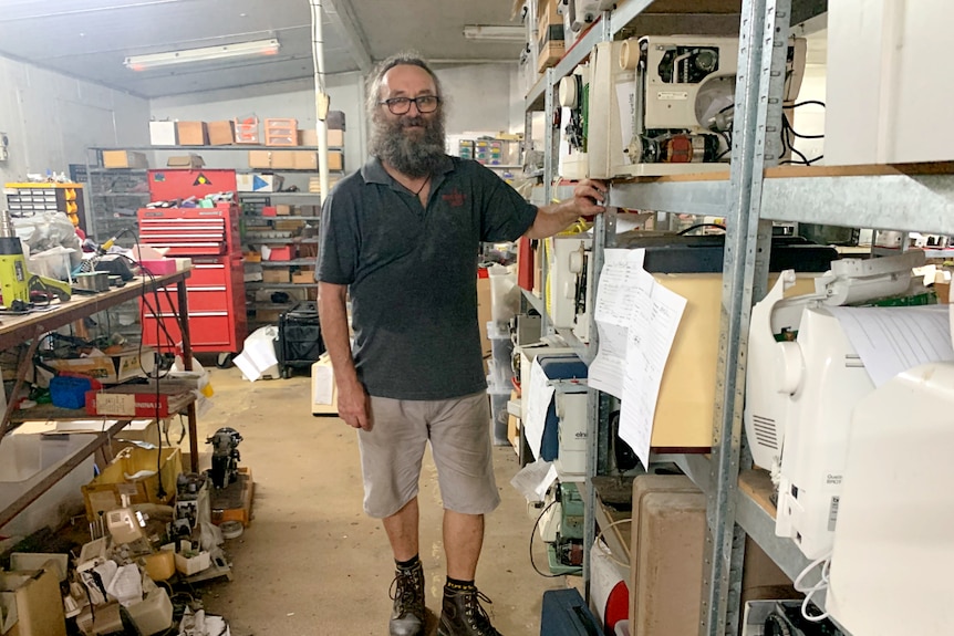 Man standing in a room of broken sewing machines