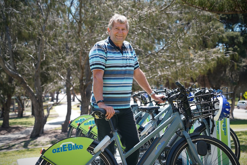 A man wearing a striped shirt poses with some bikes