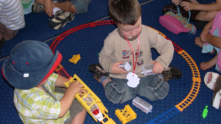 Two unidentified boys playing with trains on floor at child care centre, Canberra. Generic.