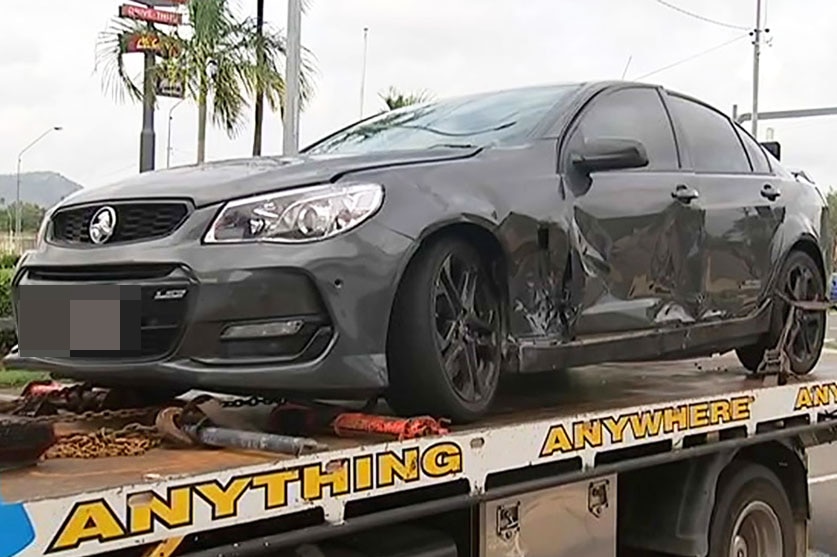 Damaged black car on back of tow truck after collision with motorcycle in Townsville.