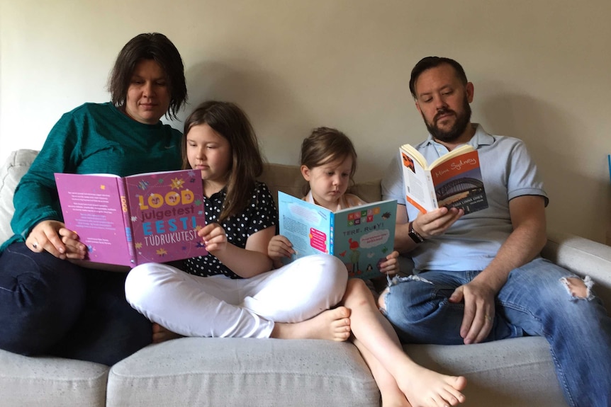 A family sitting on a couch reading kids books.