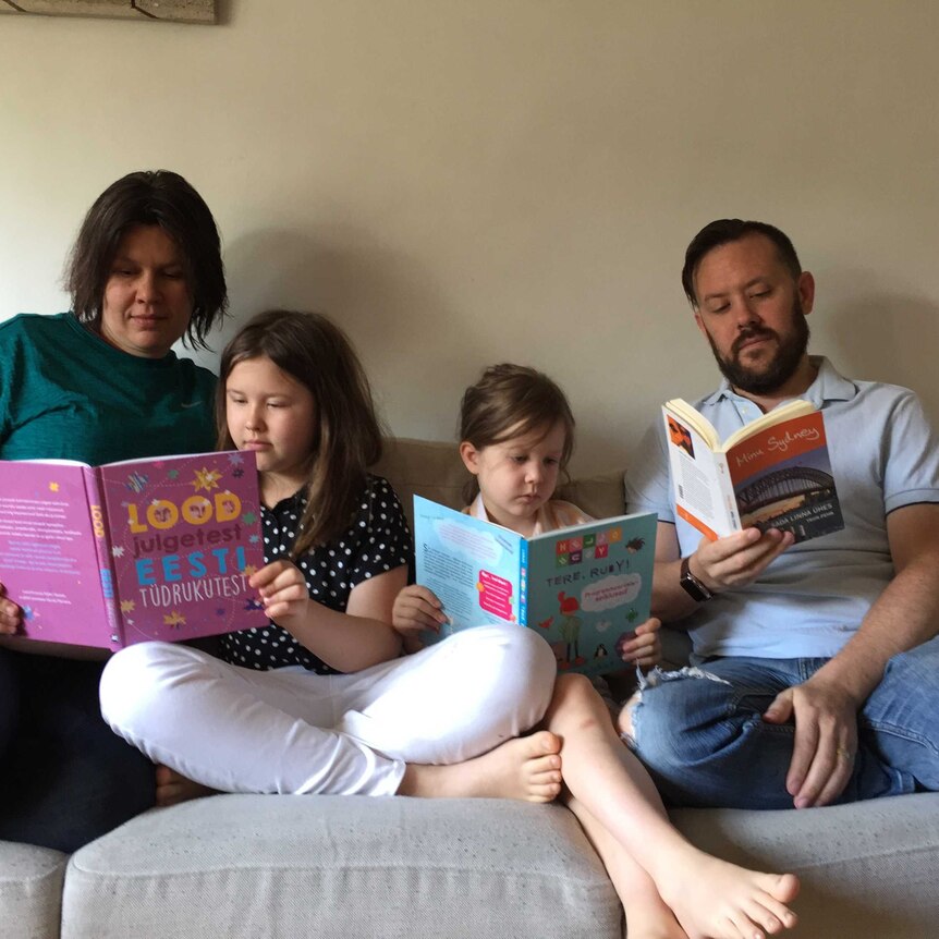 A family sitting on a couch reading kids books