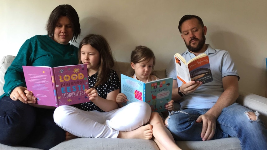 A family sitting on a couch reading kids books.