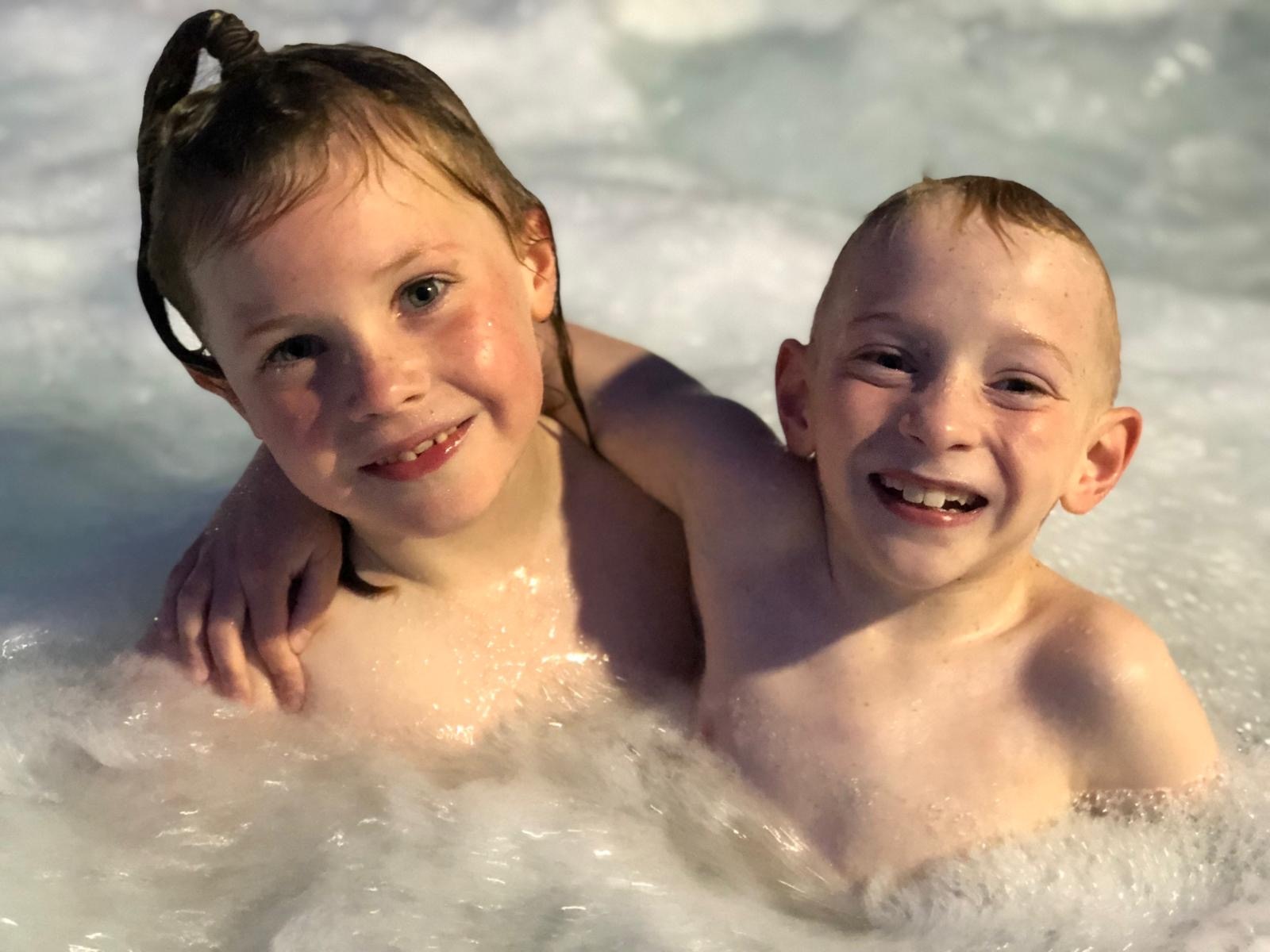 Nate Lawson and his sister smiling at the camera in the pool. 