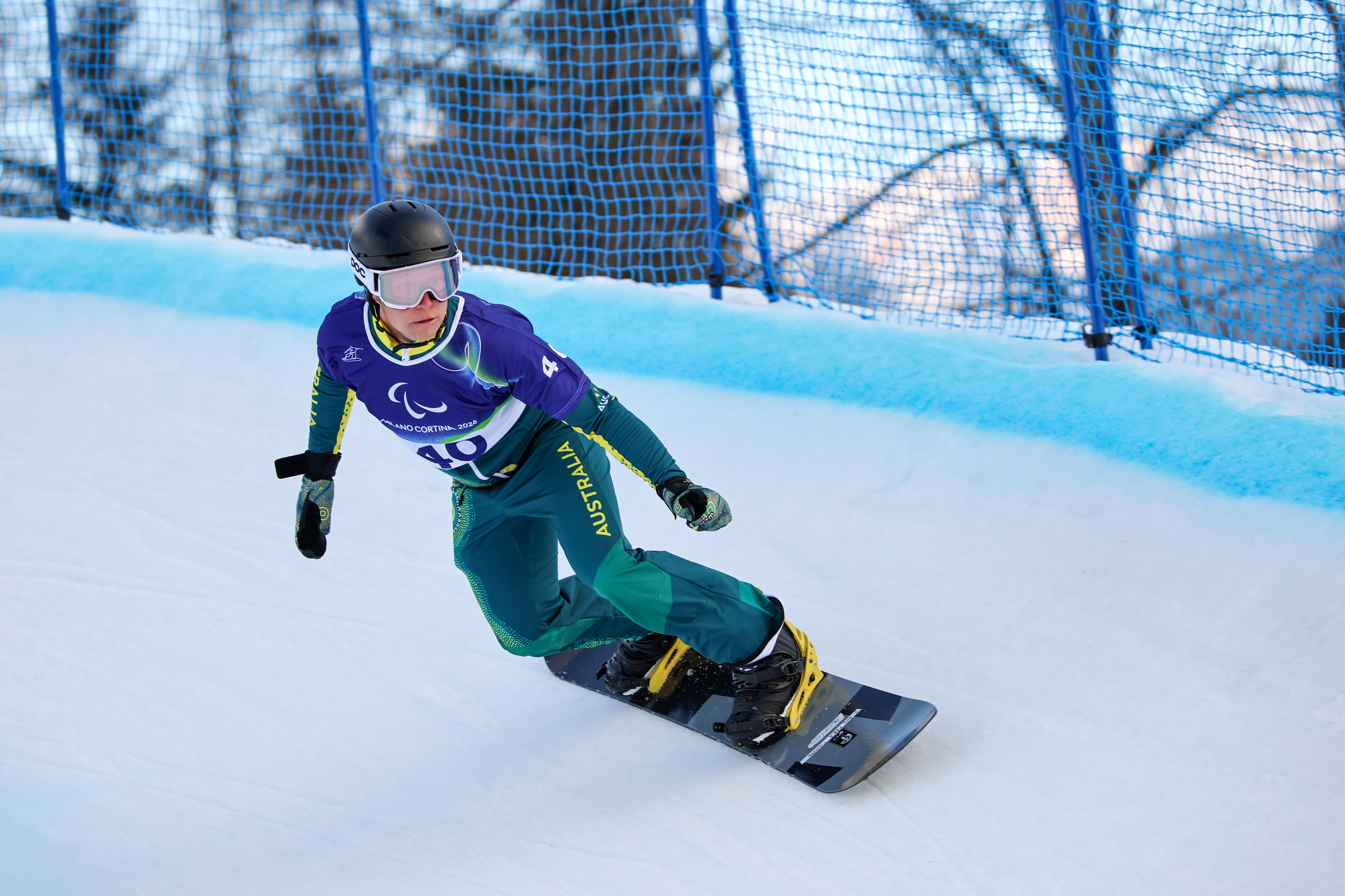 An Australian para-snowboarder angles his body as he goes into a turn in a slalom event at the Winter Paralympics.