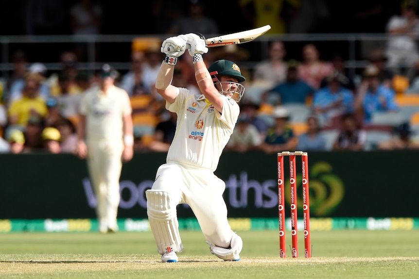 Australia batter Travis Head almost on one knee as he completes a batting stroke on day two of the first Ashes Test at the Gabba