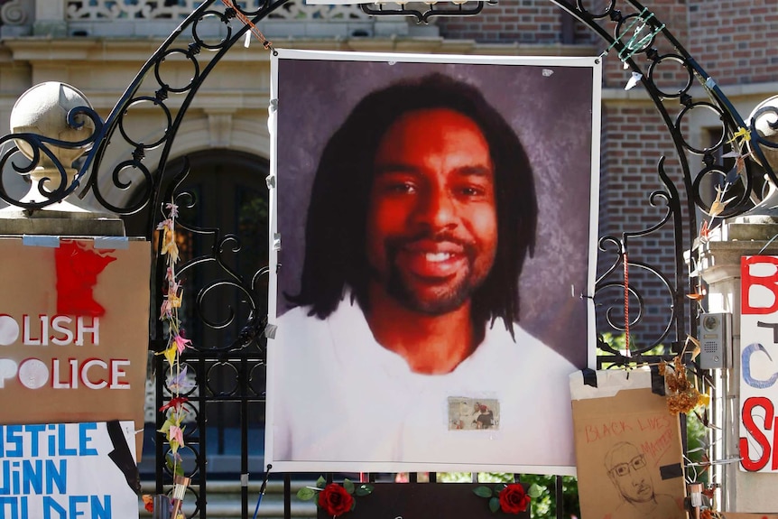 A memorial including a photo of Philando Castile adorns the gate to the governor's residence.