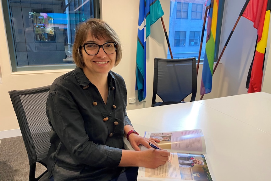 Jozica sits in an office near an Aboriginal flag.