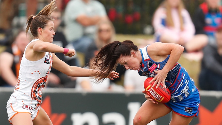 Two AFLW players tussle for the ball 