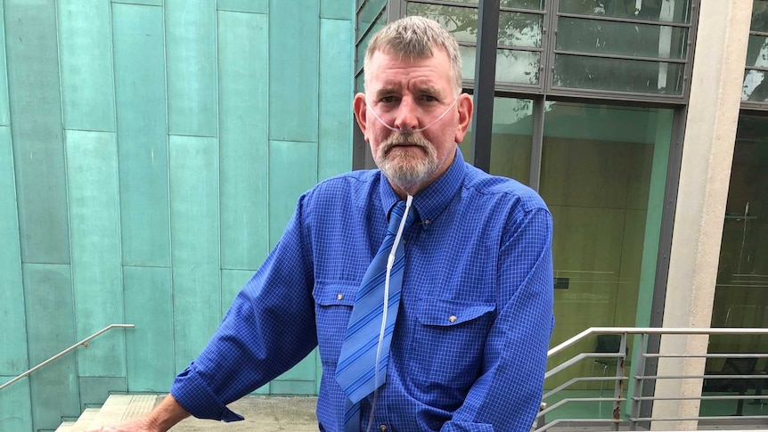 A bearded man in a blue shirt and tie