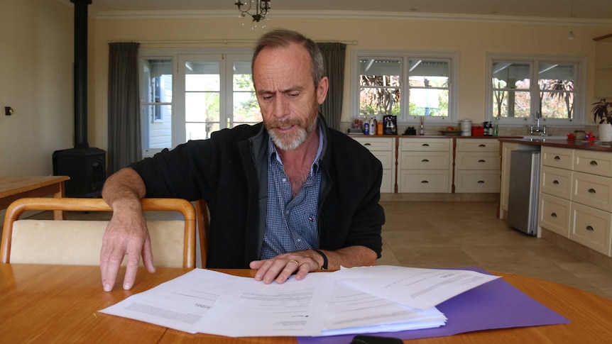 Ian sits at his kitchen table looking at documents.