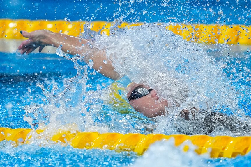 Iona Anderson splashes through the water while swimming backstroke