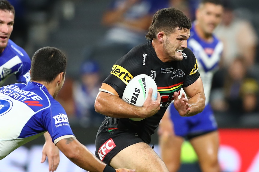 Nathan Cleary grimaces and runs with a rugby ball under his arm