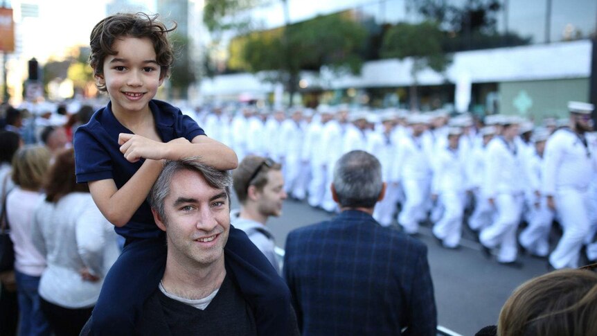 Young Davi sits on his fathers shoulders to watch the Anzac parade.