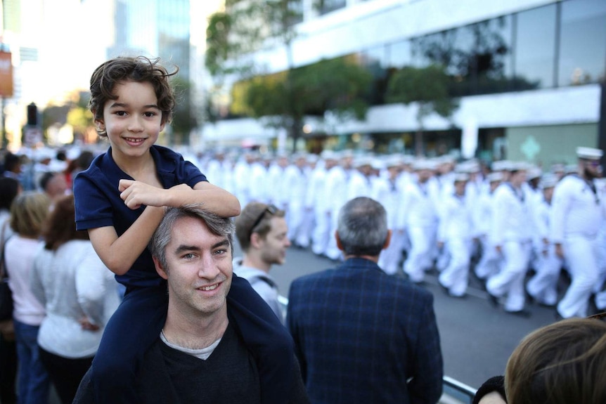 Young Davi sits on his fathers shoulders to watch the Anzac parade.