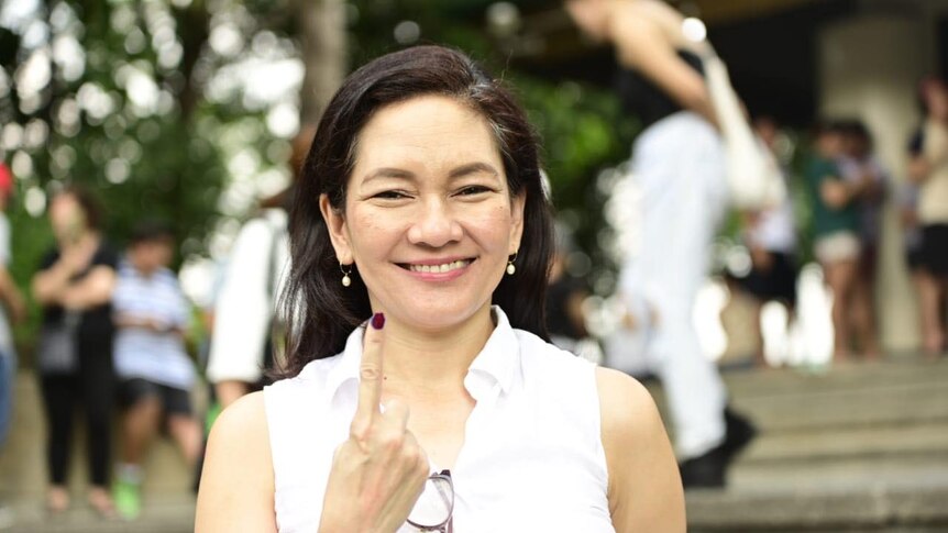 A close-up image of Risa Hontiveros in a white short pointing her right index finger in the air.