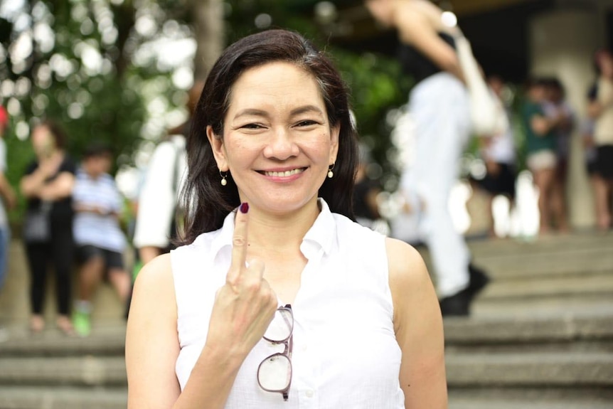 A close-up image of Risa Hontiveros in a white short pointing her right index finger in the air.