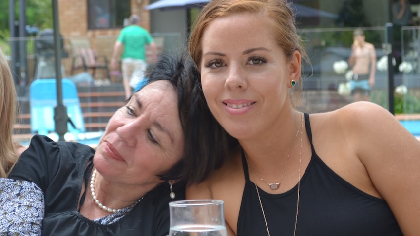 Two women lean against each other at a cafe table for a story on grief groups.