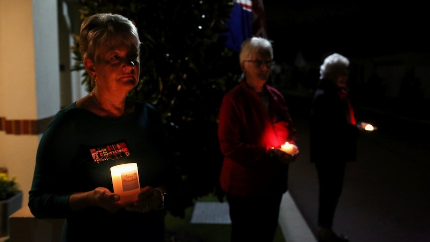 Women hold candles during Anzac Day memorial