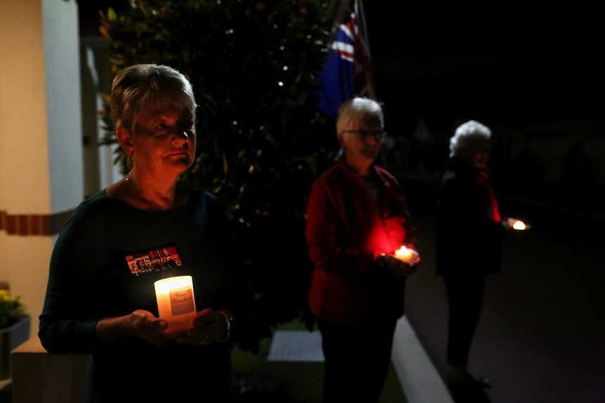 Women hold candles during Anzac Day memorial