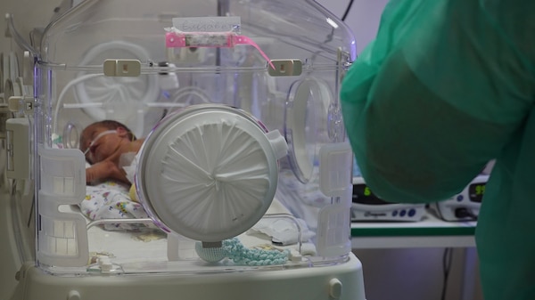 A premature baby lies inside a neo-natal incubator.